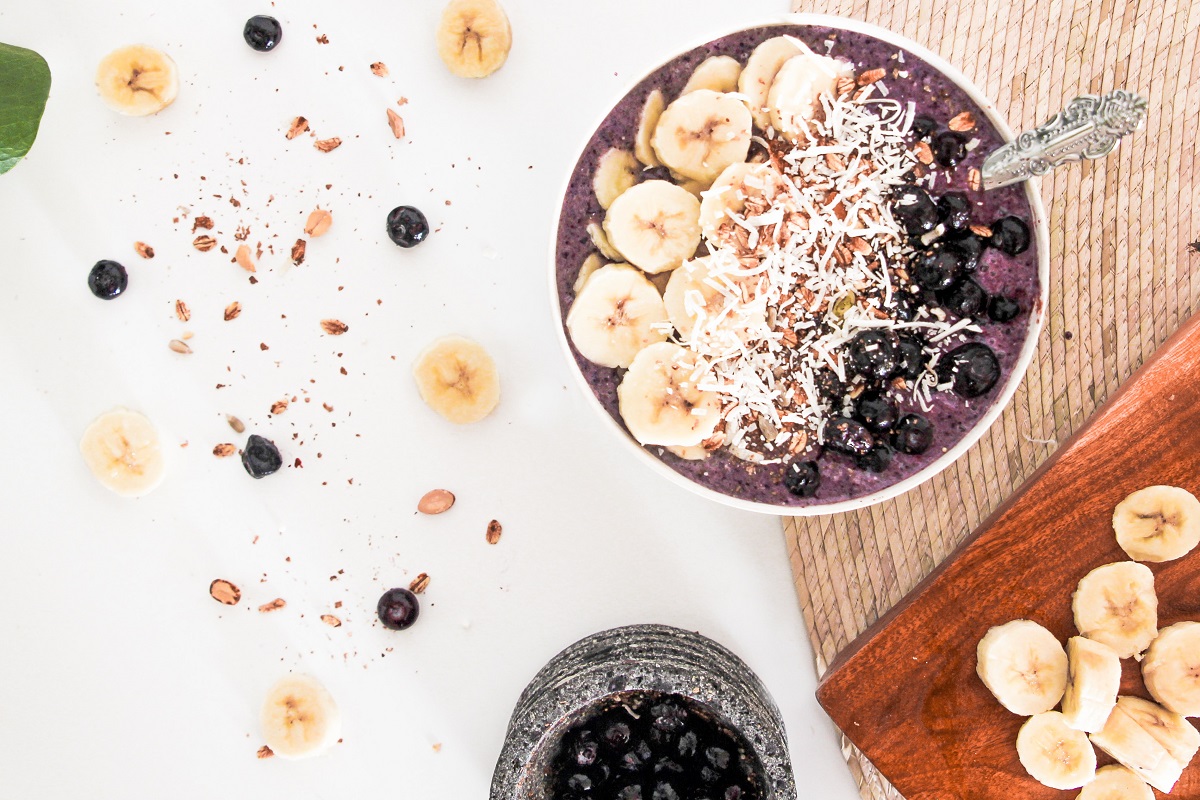 Smoothie bowl with bananas on a board.
