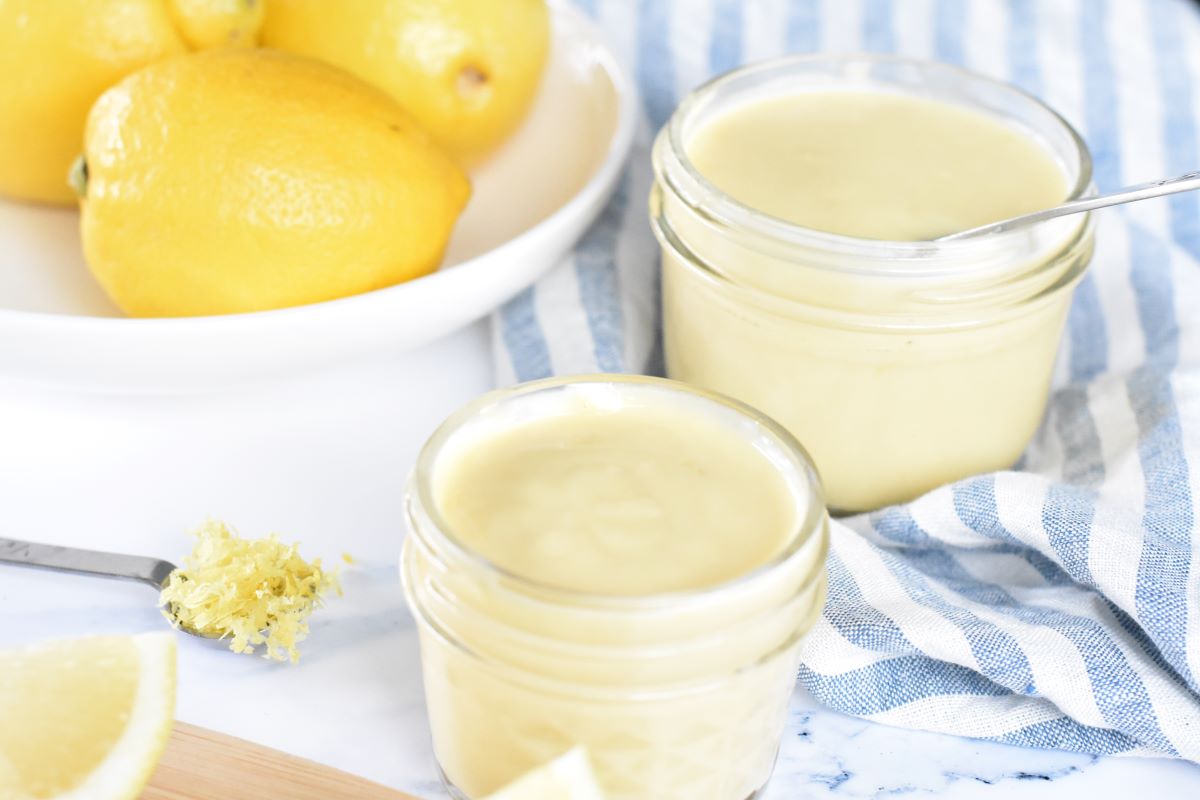 Lemon Curd in jars with a bowl of lemons.