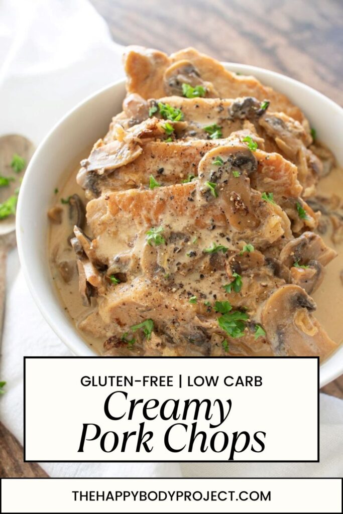 A bowl of creamy pork chops garnished with fresh parsley and pepper, with mushrooms in a sauce. Text on the image reads "Gluten-Free | Low Carb Creamy Pork Chops" and "thehappybodyproject.com".