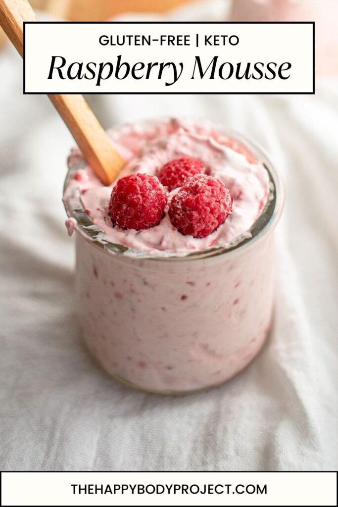 A jar of raspberry mousse topped with three fresh raspberries and a wooden spoon. The label on the image reads "Gluten-Free | Keto Raspberry Mousse." The bottom has a website URL: thehappybodyproject.com.
