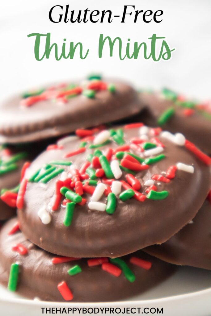 A stack of chocolate-covered cookies topped with red, green, and white sprinkles. Text reads "Gluten-Free Thin Mints" at the top and "thehappybodyproject.com" at the bottom.