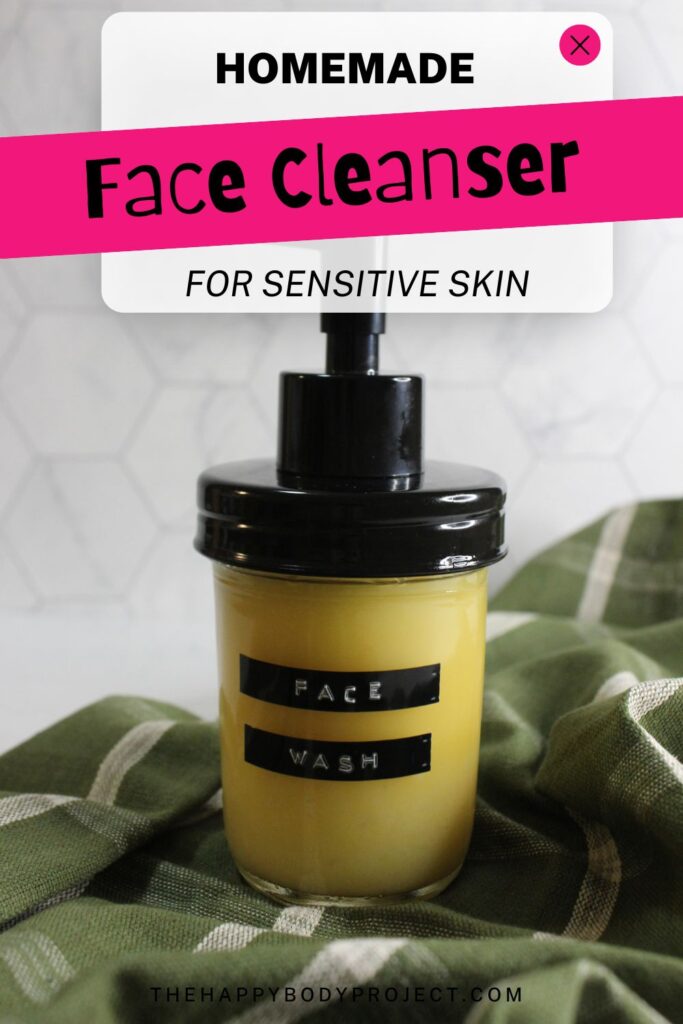 A jar with a pump dispenser labeled "Face Wash" is sitting on a green and white checkered cloth. Above it, a digital banner reads "Homemade Face Cleanser for Sensitive Skin." The background features a white hexagonal tile pattern.