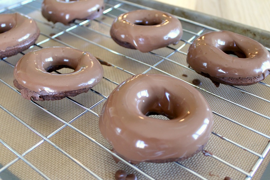 Chocolate donuts on a wire rack.